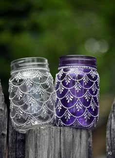 two mason jars with lace on them sitting next to each other in front of a wooden fence