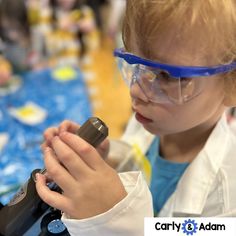 a young boy wearing goggles and holding a microscope in his hand while looking at something