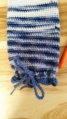 a crocheted blue and white hat sitting on top of a wooden table next to a carrot