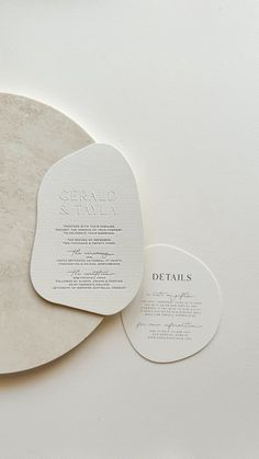 two circular tags with names on them sitting on top of a white surface next to each other