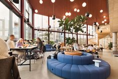 people are sitting at tables and eating in a restaurant with large windows that overlook the city