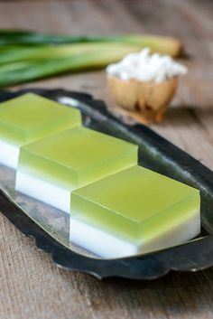 some green and white soaps on a black plate next to garlic, celery