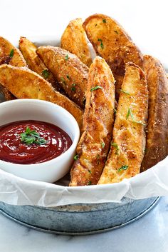 baked french fries with ketchup and parsley in a bowl on a table