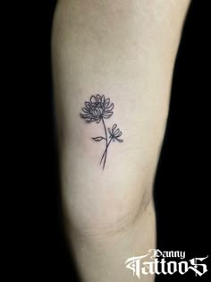 a black and white photo of a flower tattoo on the left thigh, with one single flower in it's center