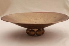 a brown bowl sitting on top of a white table next to a wooden stand with three balls in it