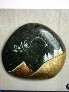 a painted rock with mountains and stars on it