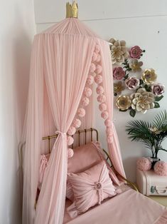 a canopy bed with pink sheets and pillows