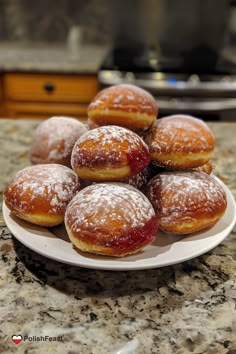 a white plate topped with donuts covered in powdered sugar on top of a counter