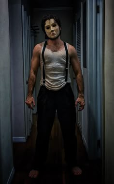 a man wearing a mask and suspenders standing in an open doorway with his hands on his hips