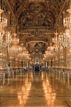 an ornate hall with chandeliers and paintings on the walls