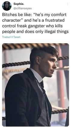 a man in a suit and tie standing next to ropes