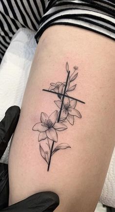 a woman's thigh with a cross and flowers tattoo on the side of her leg