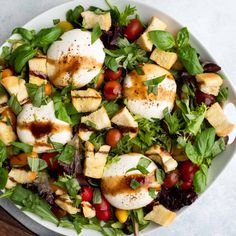 a white bowl filled with salad topped with mozzarella and chicken pieces on top of lettuce