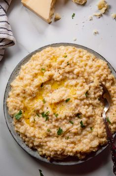 a bowl of mashed potatoes with parmesan cheese and butter on the side