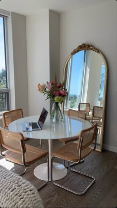 a table with chairs and a laptop on it in front of a large window overlooking the ocean