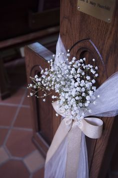 a bouquet of baby's breath is tied to the door handle on a church pew