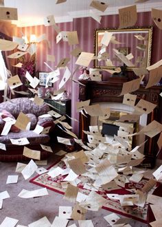 many pieces of paper are flying in the air near a couch and chair with a mirror on it