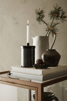 a table topped with a vase filled with flowers next to a lit candle and books