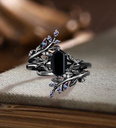 a black diamond ring sitting on top of a wooden table next to an open book