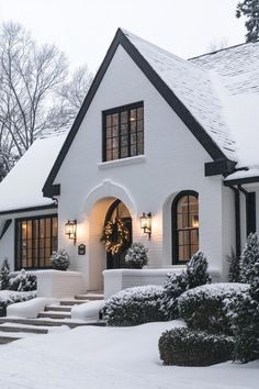 a white house with snow on the ground and steps leading up to it's front door