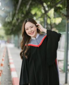 a woman in a graduation gown is posing for the camera with her hand on her head