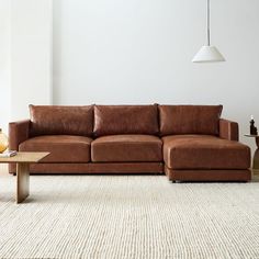 a brown leather couch sitting on top of a carpeted floor next to a table