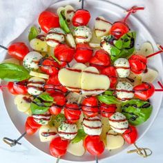 a white plate topped with tomatoes and cheese skewers