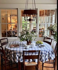 a dining room table with blue and white checkered cloth on it, surrounded by windows