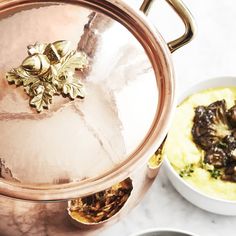 a copper pot filled with food next to other dishes