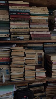 many books are stacked on top of each other in a room filled with wooden shelves