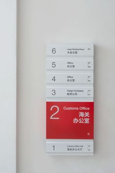 a red and white sign hanging on the wall next to a door with numbers in it