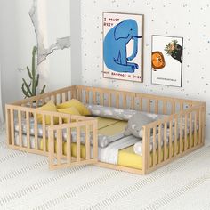 a small wooden crib in the corner of a room next to a plant and pictures