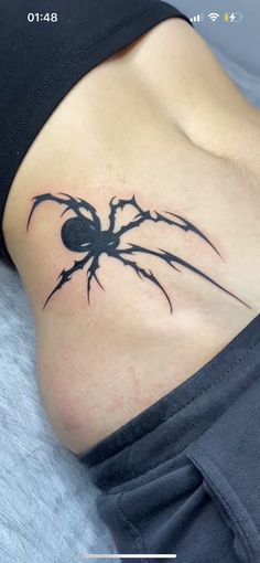 a woman's stomach with a spider tattoo on her side and the bottom part of her belly