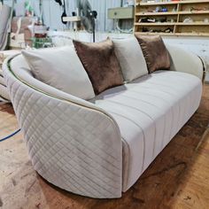 a white couch sitting on top of a hard wood floor next to a shelf filled with shelves