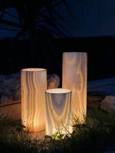 three white vases sitting in the grass at night