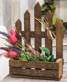 a wooden box with flowers in it sitting on the ground next to a white fence