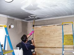 a woman is painting the ceiling in an unfinished room