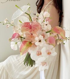 a woman holding a bouquet of flowers in her hand and wearing a white dress with the word love written on it