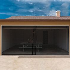 an empty garage with a picnic table in the center and a blue sky behind it