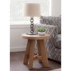 a wooden table with a lamp on it in front of a chair and couches