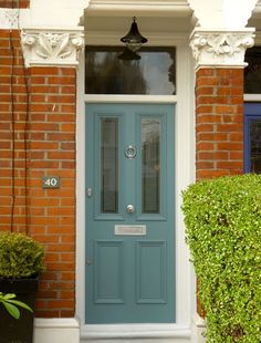 a blue front door on a brick building with potted plants in the foreground