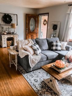 a living room filled with furniture next to a wooden table and window covered in plaid pillows