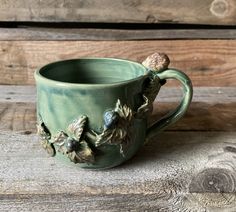 a green ceramic mug with flowers on it