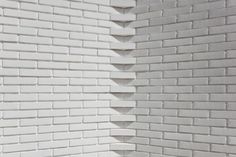 the corner of a white brick wall that is made up of several different sized bricks