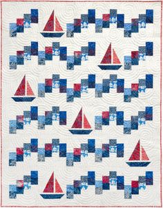 a quilted wall hanging with sailboats and squares in blue, red, and white