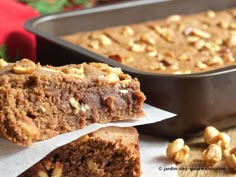 two pieces of cake sitting next to each other in front of a pan filled with nuts