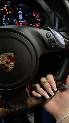 a woman's hand on the steering wheel of a car with her nails painted white