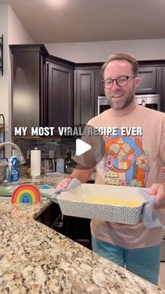 a man standing in front of a kitchen counter holding a cake pan with the words, my most virtual recipe ever