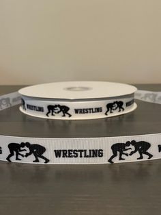 two white ribbons with black wrestling logos on them, one for the camera and one for the webcam