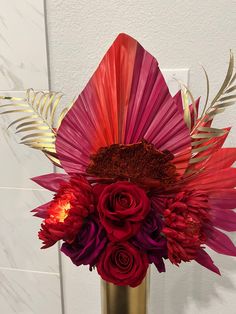 a vase filled with red and purple flowers on top of a white countertop next to a wall